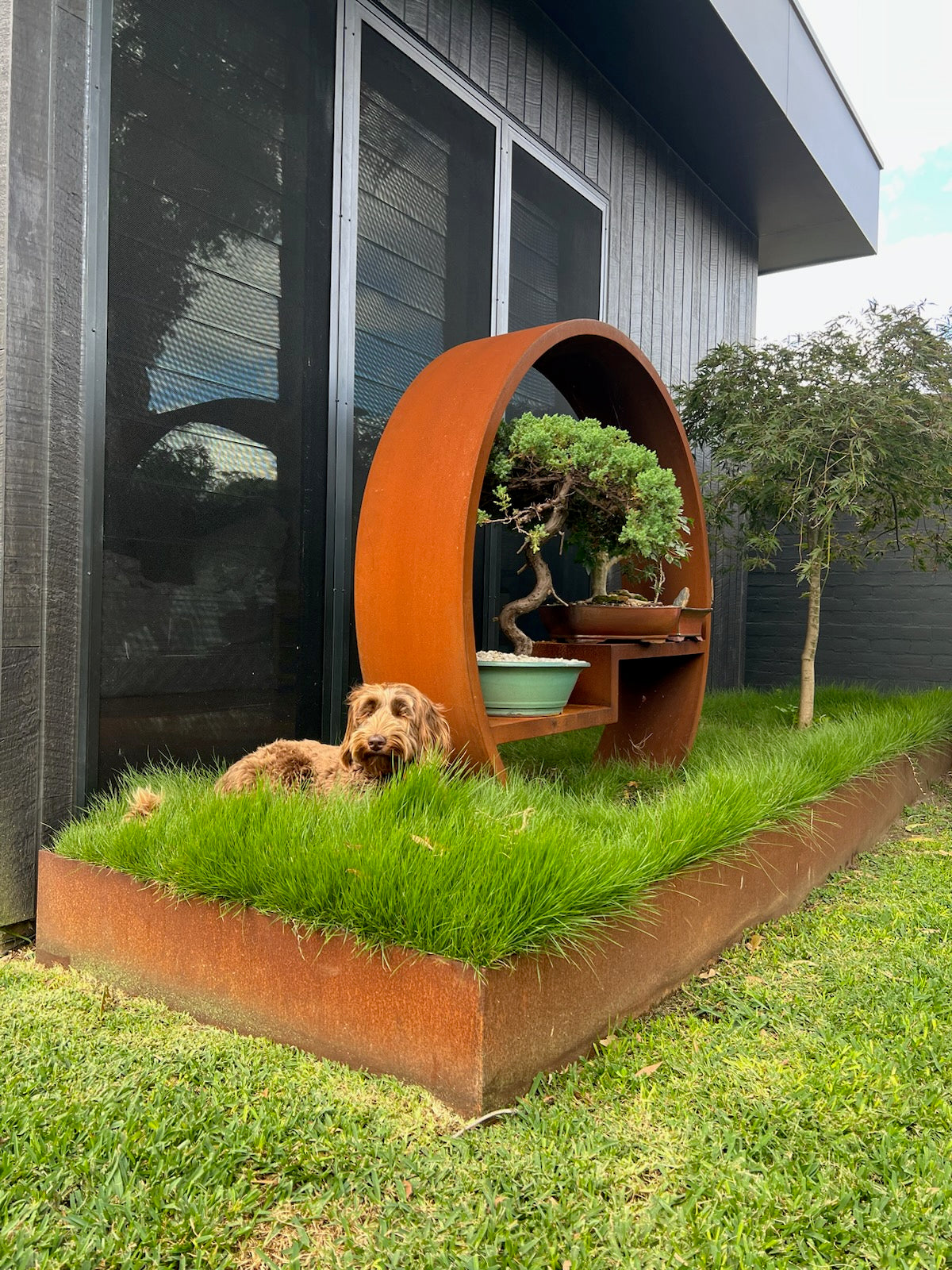 H & S Metalcraft: A custome rust steel art piece with a dog laying in the grass below it