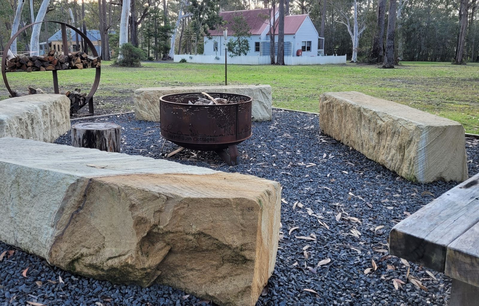 An outdoor firepit at Bay and Bush cottages made from corten steel surrounded by sandstone seats